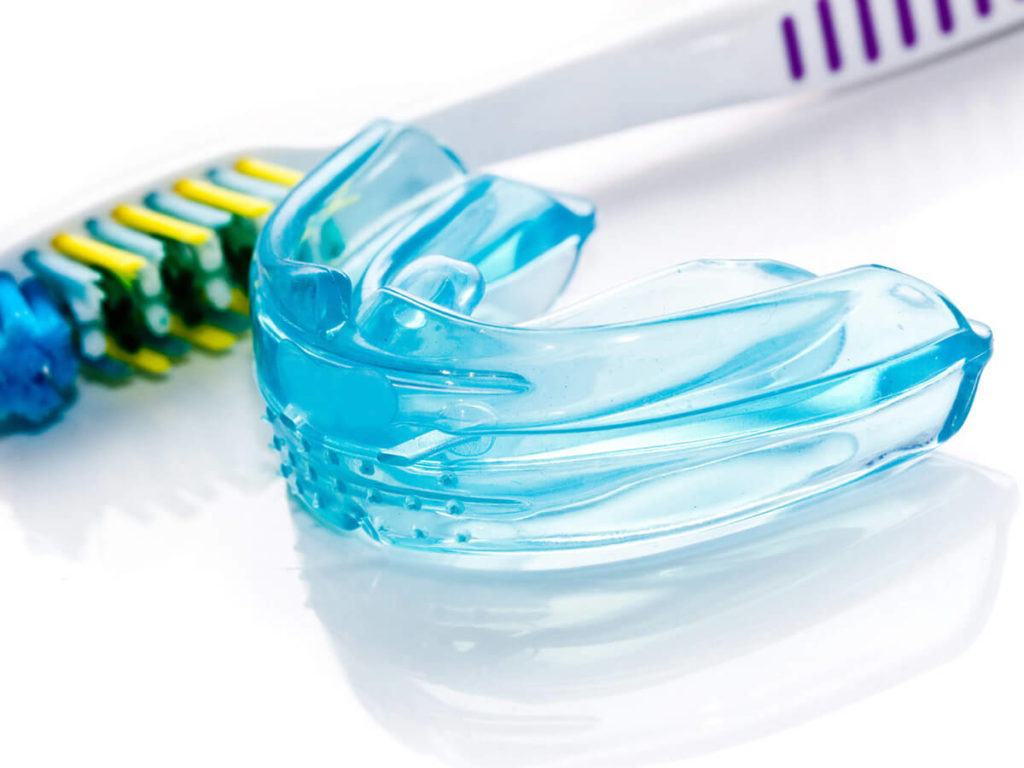 Photo of a plastic mouthguard next to a toothbrush