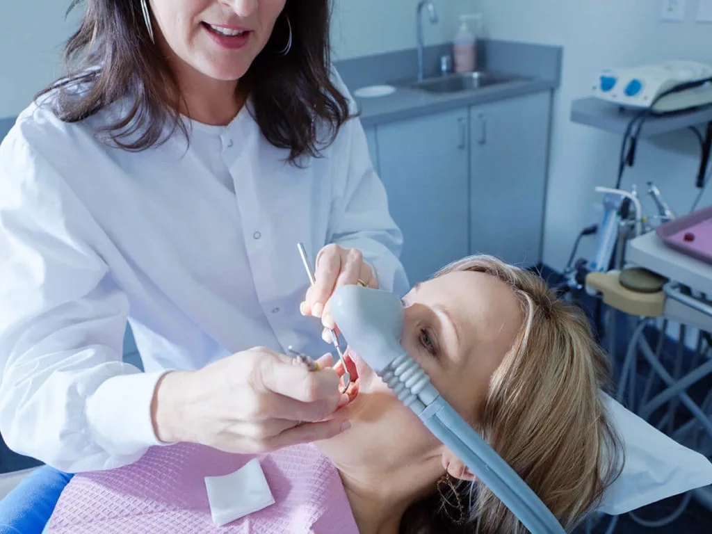 Photo of a dentist providing sedation to a patient.